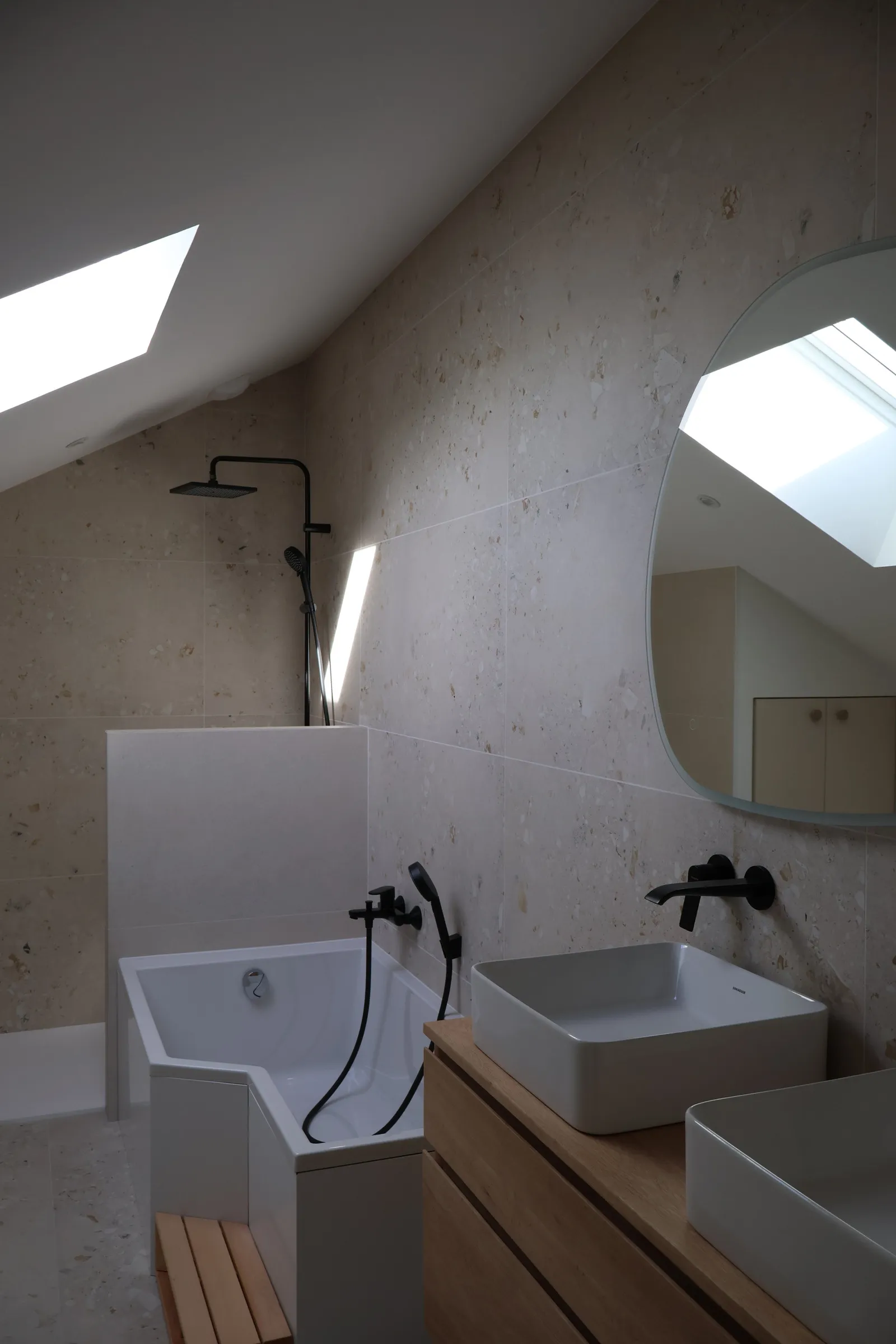 Salle de bain sous combles d'une maison neuve, baignoire îlot, double vasque et velux.