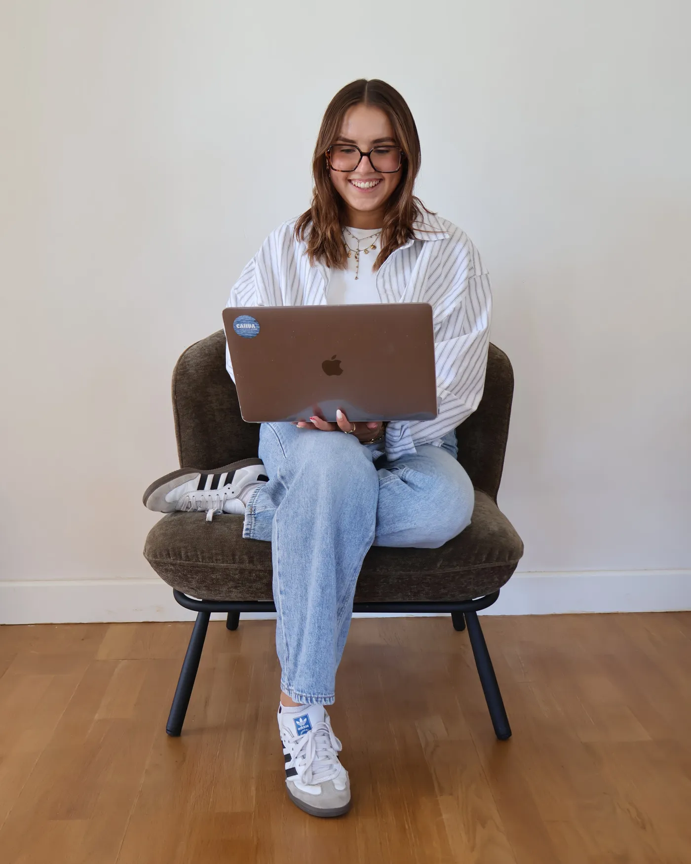 Fleurine Vinet, souriante, assise dans un fauteuil, son ordinateur portable sur les genoux.